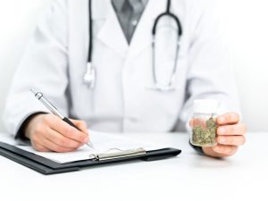 a doctor holding some cannabis and writing a prescription